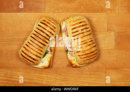 Ham, cheese and onion panini on a wooden chopping board Stock Photo