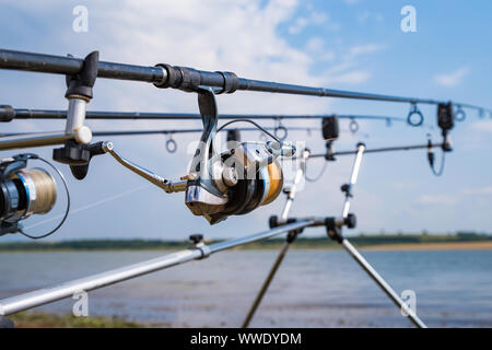 Two fishing rods mounted on the holder and set up at the shore of a lake.  Beautiful lake view with yellow catamaran Stock Photo - Alamy