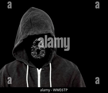 Hooded menacing man with unseen face wearing a black top with a computer lock which has been broken by the hackers criminal work Stock Photo