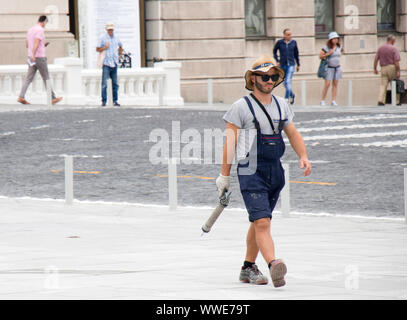 Belgrade, Serbia -  September 3, 2019: Young and handsome construction worker in casual summer outfit on city pavement holding  a caulking gun Stock Photo