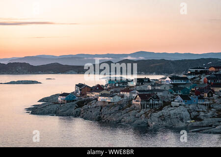 Aerial View of Arctic city of Ilulissat, Greenland during sunrise sunset with fog. Colorful houses in the center of the town with icebergs in the Stock Photo