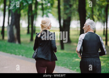 back view of mature, sportive joggers running together in park Stock Photo