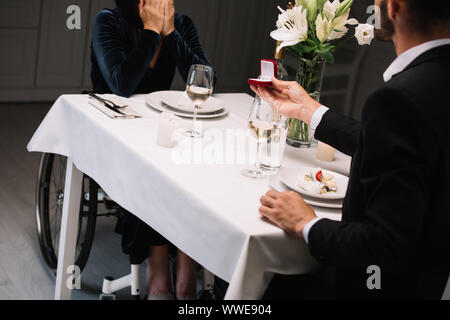 cropped view of man making wedding proposal to disabled girlfriend during romantic dinner Stock Photo