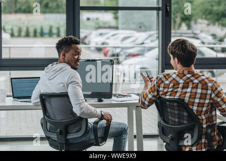 back view of young programmer talking to african american colleague in office Stock Photo