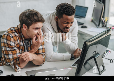 two worried multicultural programmers looking at laptop in office Stock Photo