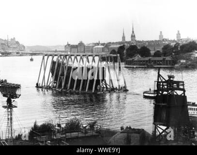 AJAXNETPHOTO. APRIL, 1961. STOCKHOLM, SWEDEN. - ANCIENT WARSHIP SALVAGE - THE WASA (VASA), FLAGSHIP OF KING GUSTAVUS ADOLPHUS WHICH SANK OUTSIDE STOCKHOLM HARBOUR IN 1628, RECOVERED AFTER A MASSIVE SALVAGE OPERATION FROM THE ICY WATERS OF THE CITY HARBOUR, IS FLOATED ON A SPECIAL CONCRETE PONTOON TO THE VASAVARVET (WASA SHIPYARD).  PHOTO: MARITIME MUSEUM AND WARSHIP WASA/AJAX REF: WASA 1961 02 Stock Photo