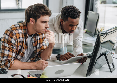 two thoughtful multicultural programmers working at workplace together Stock Photo