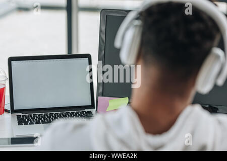 back view of african american programmer sitting at workplace in headphones Stock Photo