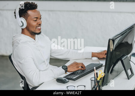 happy african american programmer sitting at workplace in headphones Stock Photo