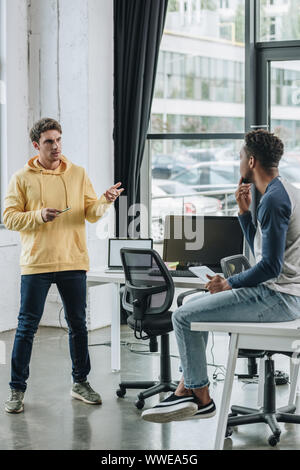 two multicultural programmers discussing ideas in office Stock Photo