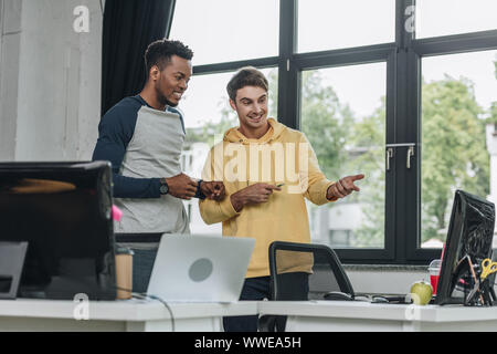 smiling multicultural programmers looking at computer monitor together Stock Photo