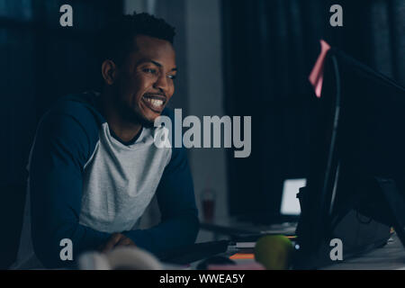 cheerful african american programmer smiling while looking at computer monitor Stock Photo