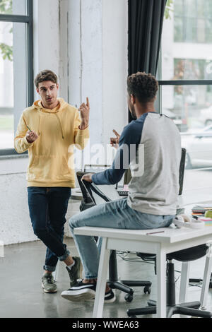 two young multicultural programmers discussing ideas in office Stock Photo