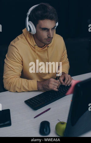 young programmer in headphones working at night in office Stock Photo