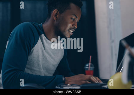 smiling african american programmer sitting at workplace at night Stock Photo