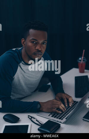 serious african american programmer looking at camera while working at night in office Stock Photo