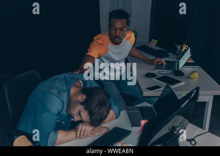 young african american programmer awakening colleague at night in office Stock Photo