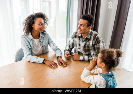 happy african american family sitting before table, smiling and looking at each other Stock Photo