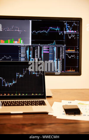 laptop and computer with charts and graphs, documents and smartphone on table Stock Photo