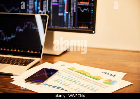 laptop and computer with charts and graphs, documents and smartphone on table Stock Photo