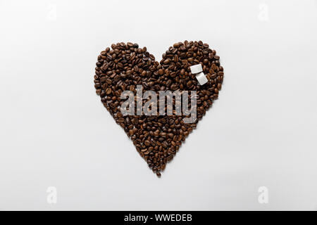 top view of heart made of coffee grains with sugar on white background Stock Photo