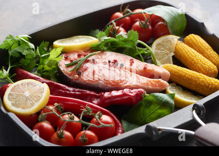 raw salmon steak with spices, vegetables and greenery in grill pan Stock Photo