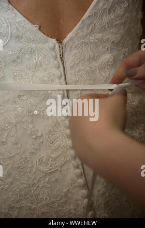 Wedding dress being done up on a Brides wedding day, close up of wedding dress being done up before the ceremony Stock Photo