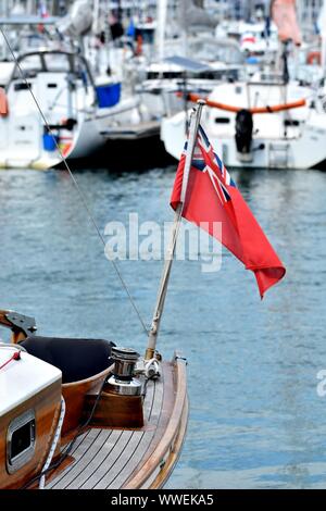 Wooden sailboat moored at the marina. Details of classic beautiful sailing yacht with teak deck, winch and British flag on blurred background Stock Photo