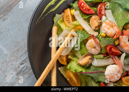 Freshly prepared Seafood salad bowl on wooden background Stock Photo