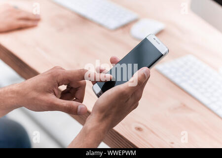 close up. businessman uses his smartphone in the workplace. Stock Photo