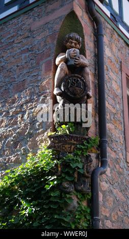 Carved figure of beer Drinker on a Barrel on Corner of House Stock Photo