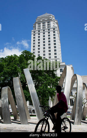 Man riding bicycle in front of  historic Miami-Dade County Courthouse building in Downtown Miami, Florida Stock Photo