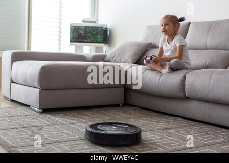 Kid with robot vacuum cleaner playing it at home Stock Photo