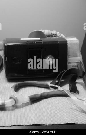 CPAP Machine, hose, and nasal mask sitting on a night stand Stock Photo