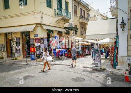 ATHENS GREECE - JULY 15 2019; Plaka street corner with tee shirt shop and man and woman Stock Photo