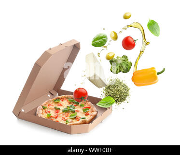 Tasty pizza in box with falling ingredients on white background Stock Photo