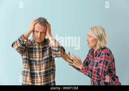 Quarrelling middle-aged couple on color background Stock Photo