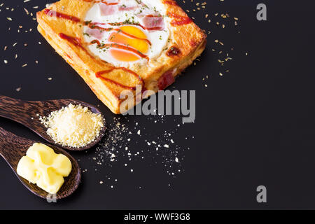 Baked bread and egg on black background, selective focus Stock Photo