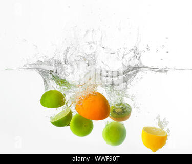 Falling of different fruits into water on white background Stock Photo