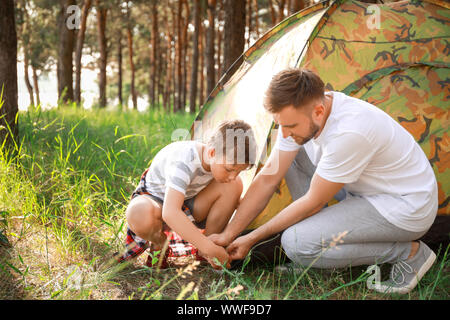 Father and his little son putting up camping tent in forest Stock Photo