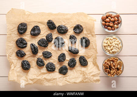 Tasty prunes with nuts on white wooden background Stock Photo