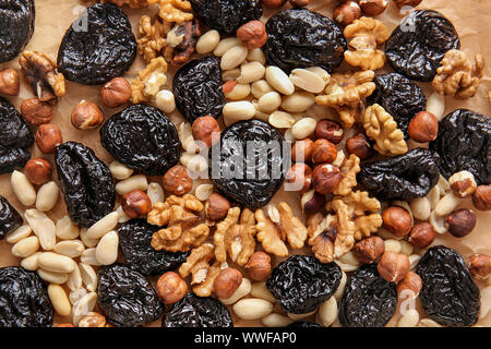 Tasty prunes with nuts on parchment, top view Stock Photo