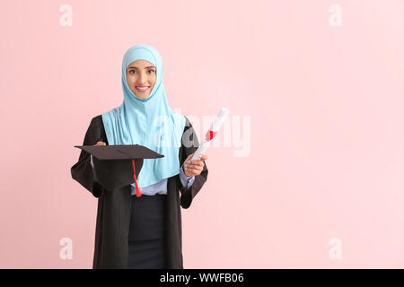 Muslim female graduate with diploma on color background Stock Photo