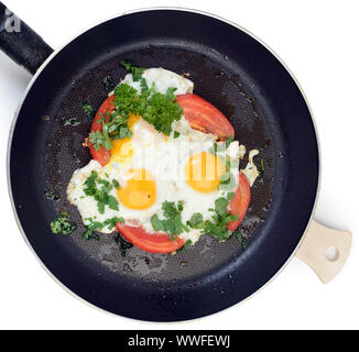 Fried eggs in pan with tomatoes and herbs. Clipping path Stock Photo