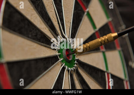 A dart hits the center of the darts board also known as 'bulls eye' . Stock Photo