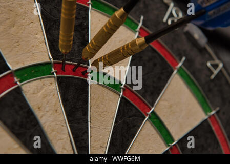 Three darts accurately hit the same area of a dart board Stock Photo