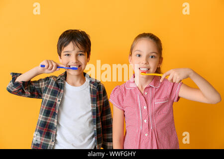 Cute little children cleaning teeth against color background Stock Photo