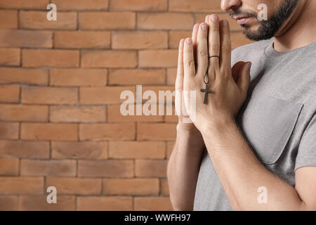 Religious man praying against brick wall Stock Photo