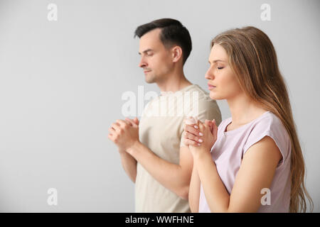 Religious couple praying to God on light background Stock Photo