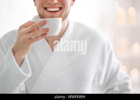 Young man in bathrobe drinking coffee at home Stock Photo